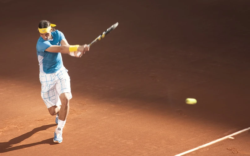 a man in blue is playing tennis and has a yellow head band