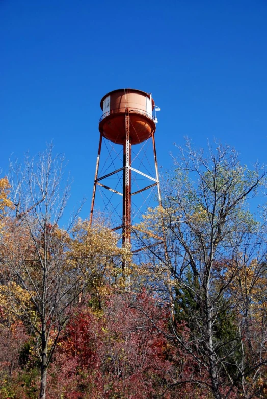 a brown water tower is standing near the trees