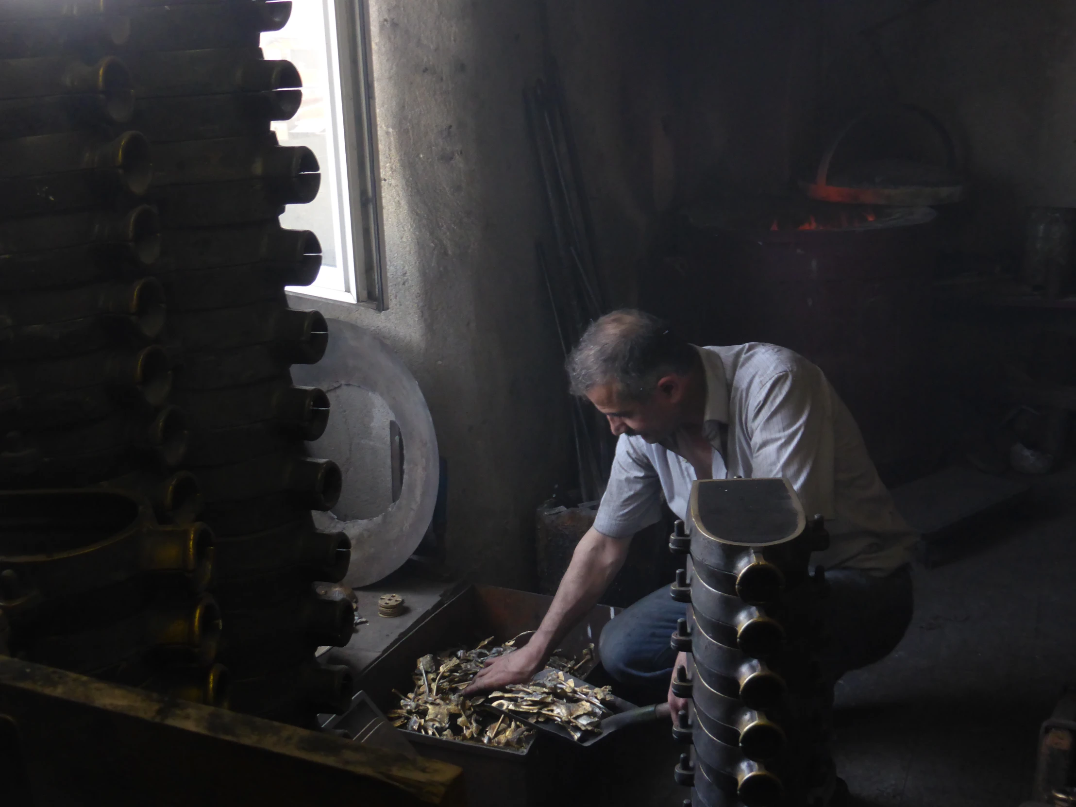 a man kneeling down in a room filled with wooden shoes