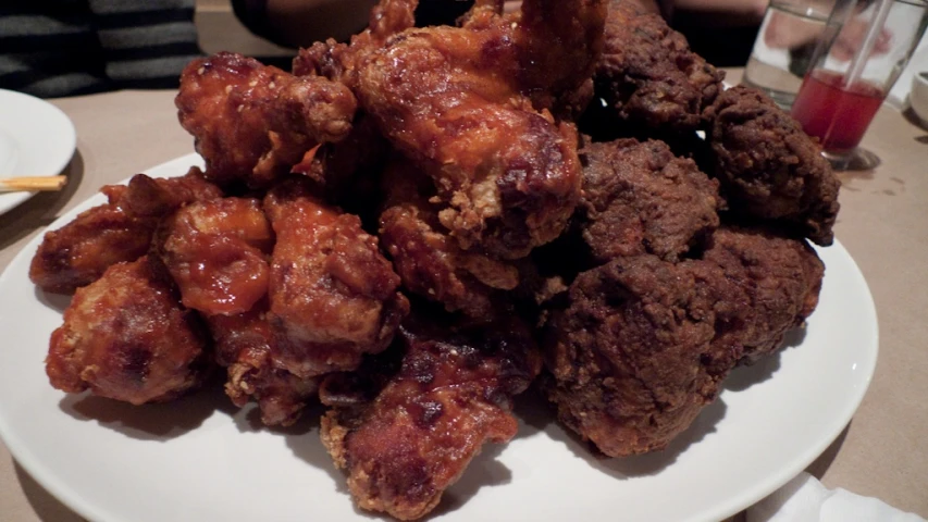 fried meat sits on a plate with a cup next to it