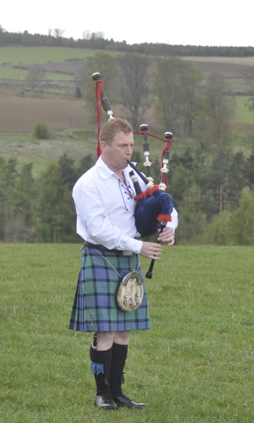 a man playing the bagpipe in a scottish outfit