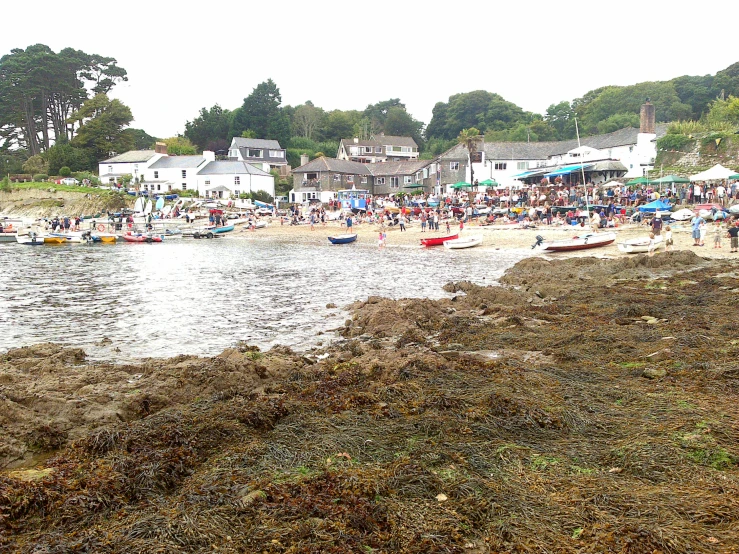 the beach has many people in it and small boats are parked