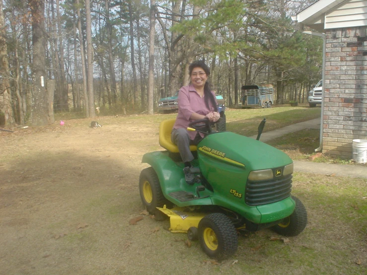 woman riding on a lawn mower and smiling in the background