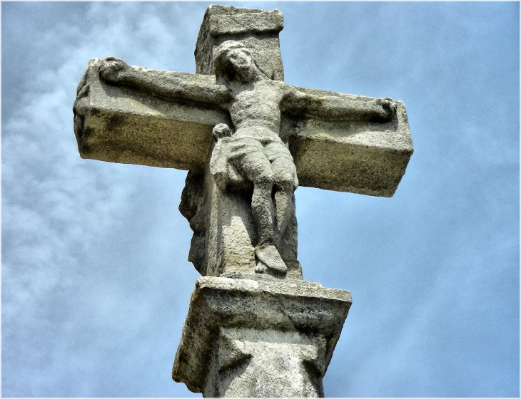 a stone cross with statue of a woman