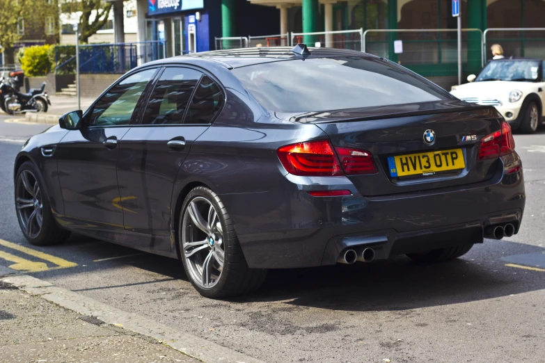 the rear end of a gray car in front of another car