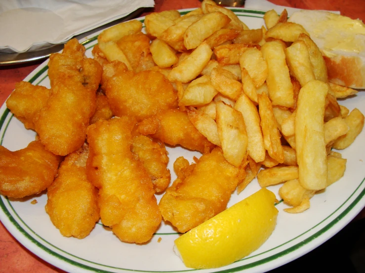 a white plate topped with fried potatoes and slices of lemon