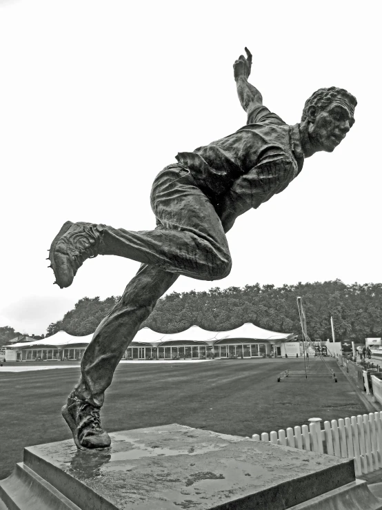 black and white pograph of a statue of a boy in the air with his leg high above him