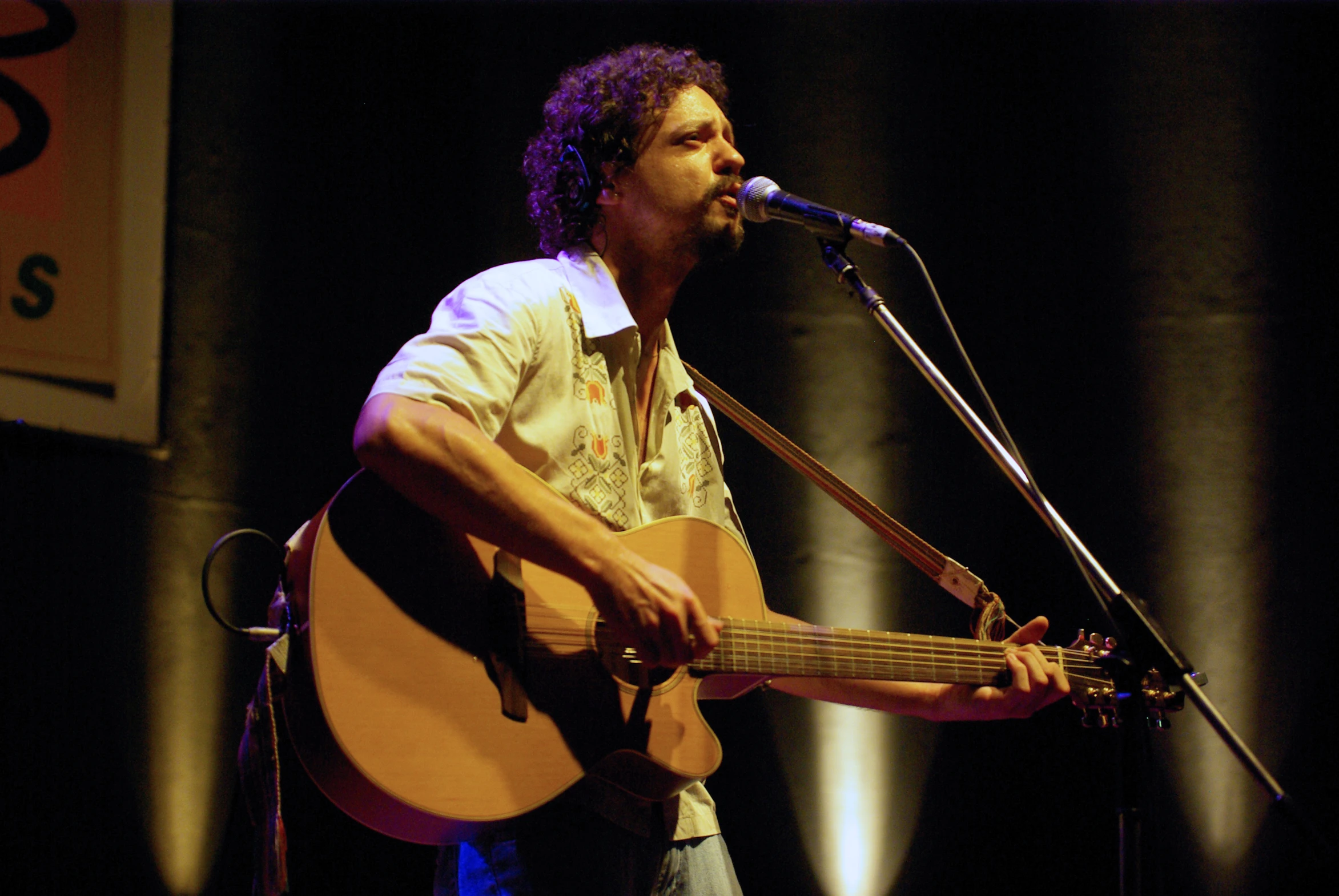 a man standing in front of a microphone while holding a guitar
