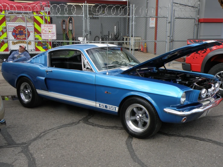 a blue car with the hood up parked in a lot