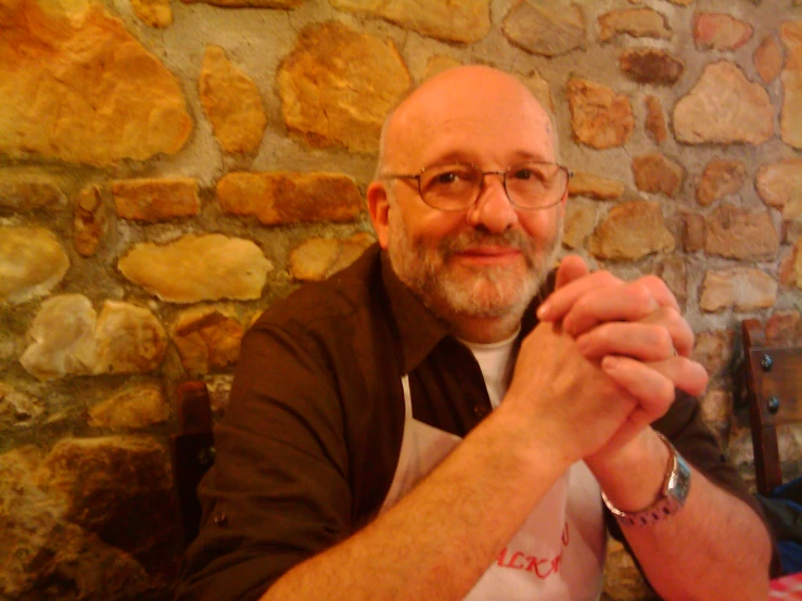 man with glasses sitting in a chair smiling at camera