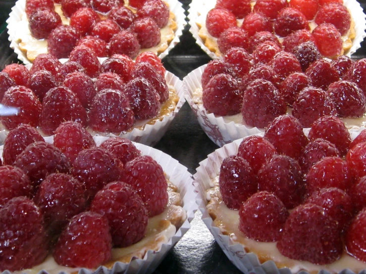 several raspberries and pastries sit on trays