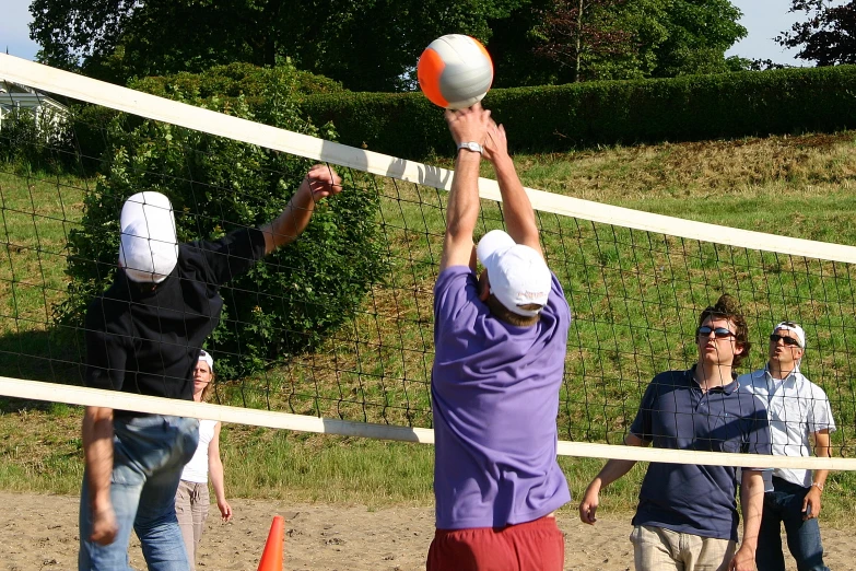 a man is hitting an orange and white volleyball on a court