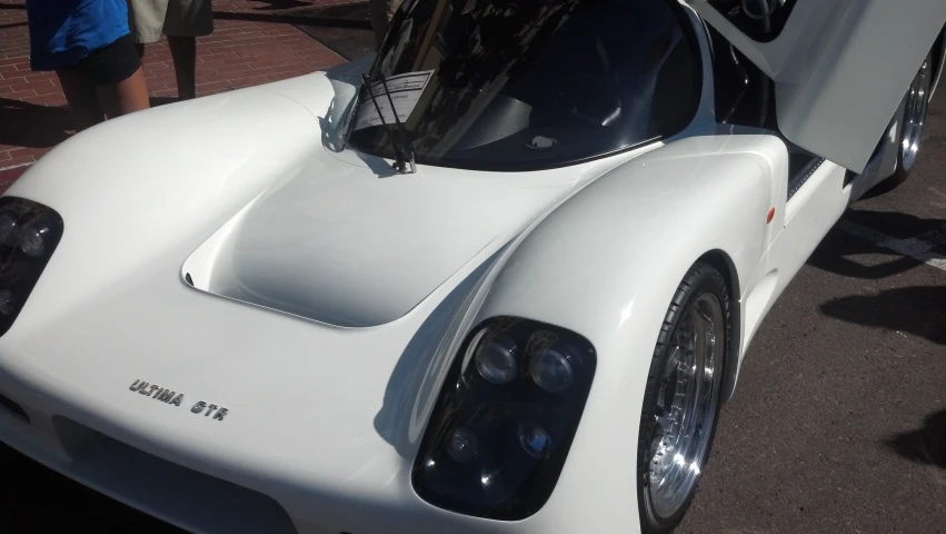 a white sports car parked next to a man