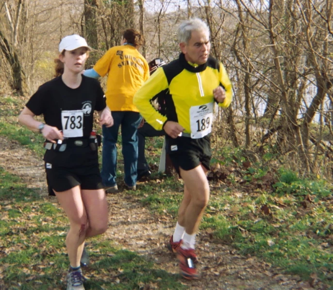 three runners in race shirts and shorts run down a path