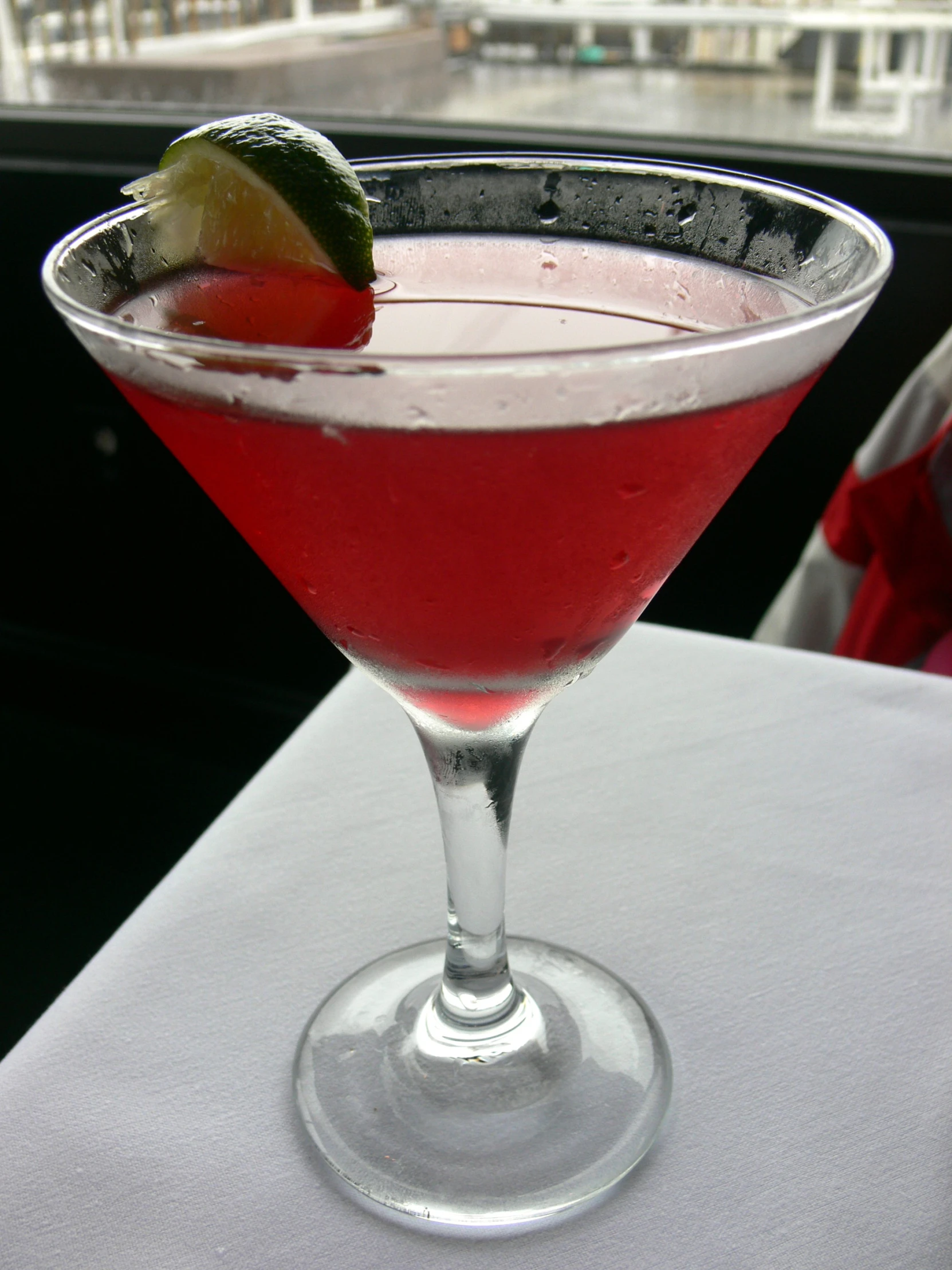 a red martini with a lime wedge on the rim