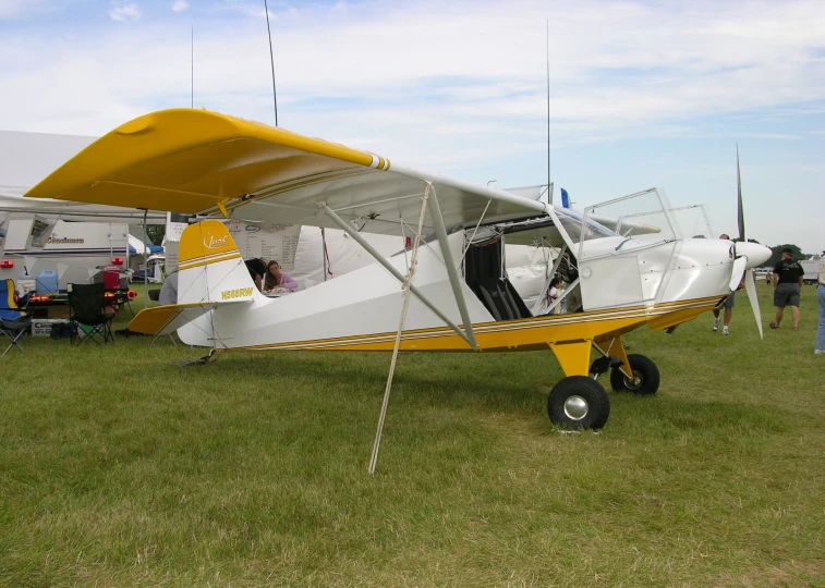 small yellow and white airplane sitting on top of a field