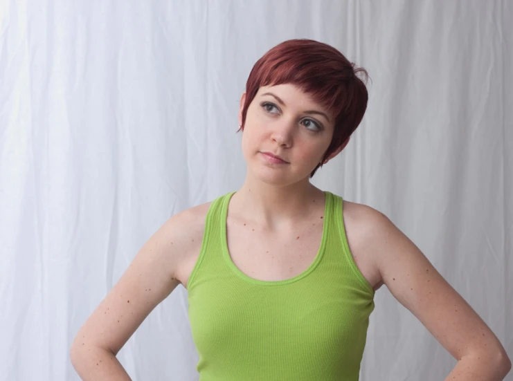 a woman in a green shirt posing with her hands on her hips