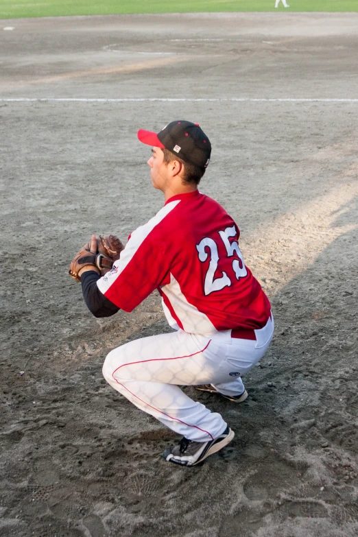 a baseball player kneeling on the ground waiting to catch a ball