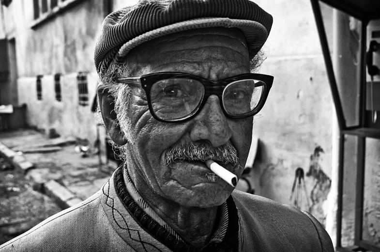 a man with glasses, cap and mustache smoking a cigarette