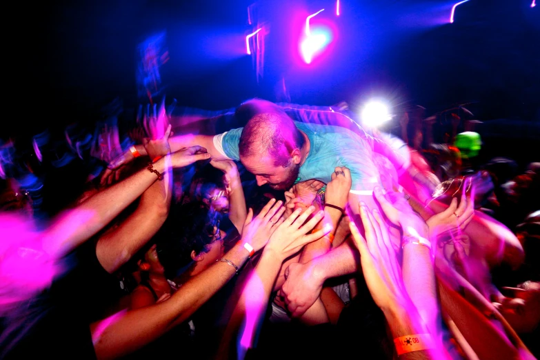 a man being hugged in the middle of crowd at a nightclub