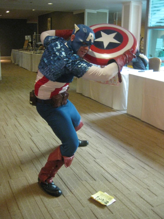 a man holding a captain america balloon in an empty room