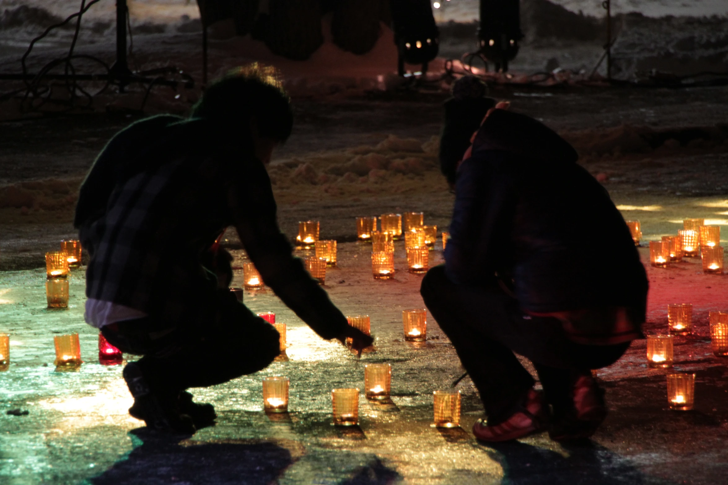 two people kneeling down near many lit candles