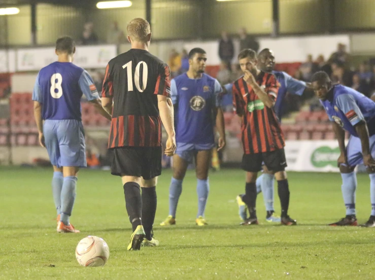 several men standing around a soccer ball on the field