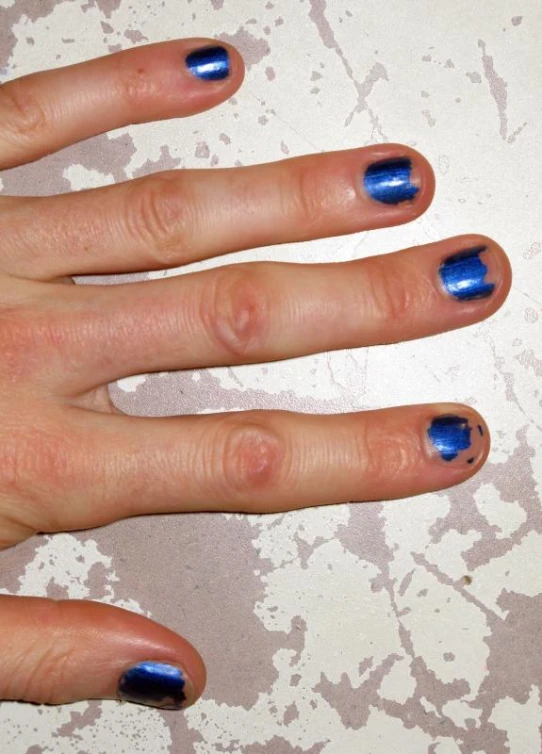 a woman with two blue fingernails and a ring