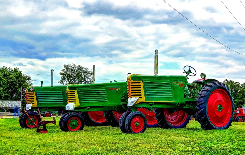 two tractors in a field of grass near power lines