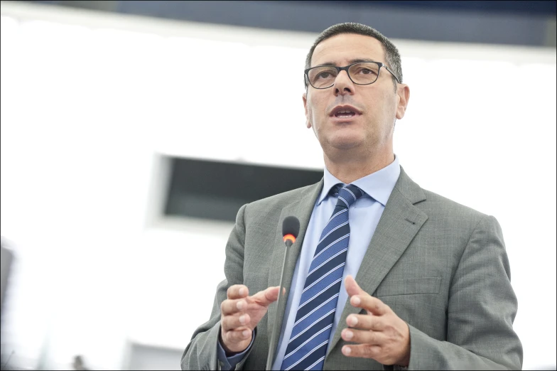 a man wearing glasses talking into microphone