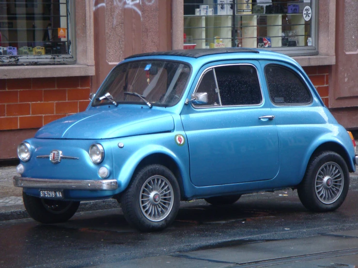 a small blue car is parked on the side of a street