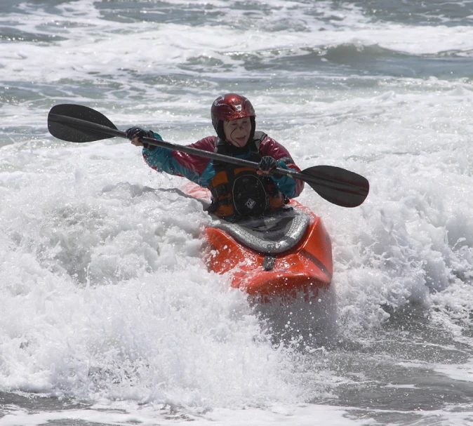 man with kayak riding an orange paddle in the ocean