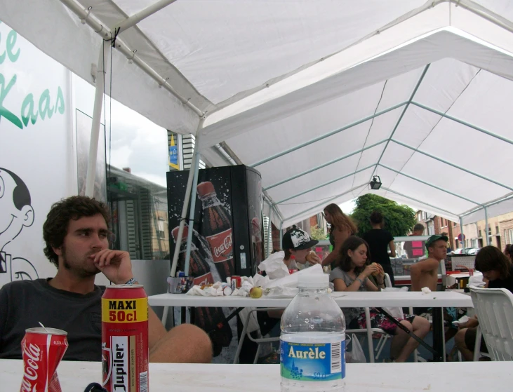 a man drinking water near two soda cans