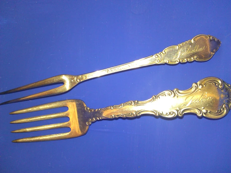 two antique silver forks with ornate designs on them