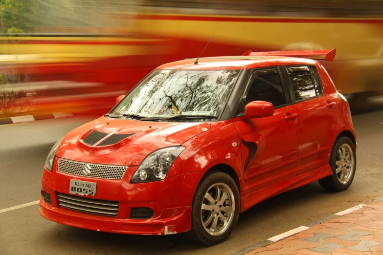 a red car is on the street, with a bus in the background