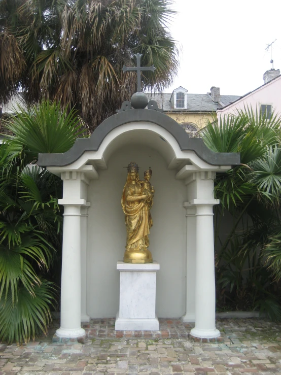 a statue under a cross in the middle of the garden