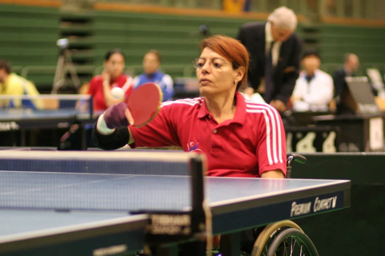 the lady sits at the table ready to play ping pong