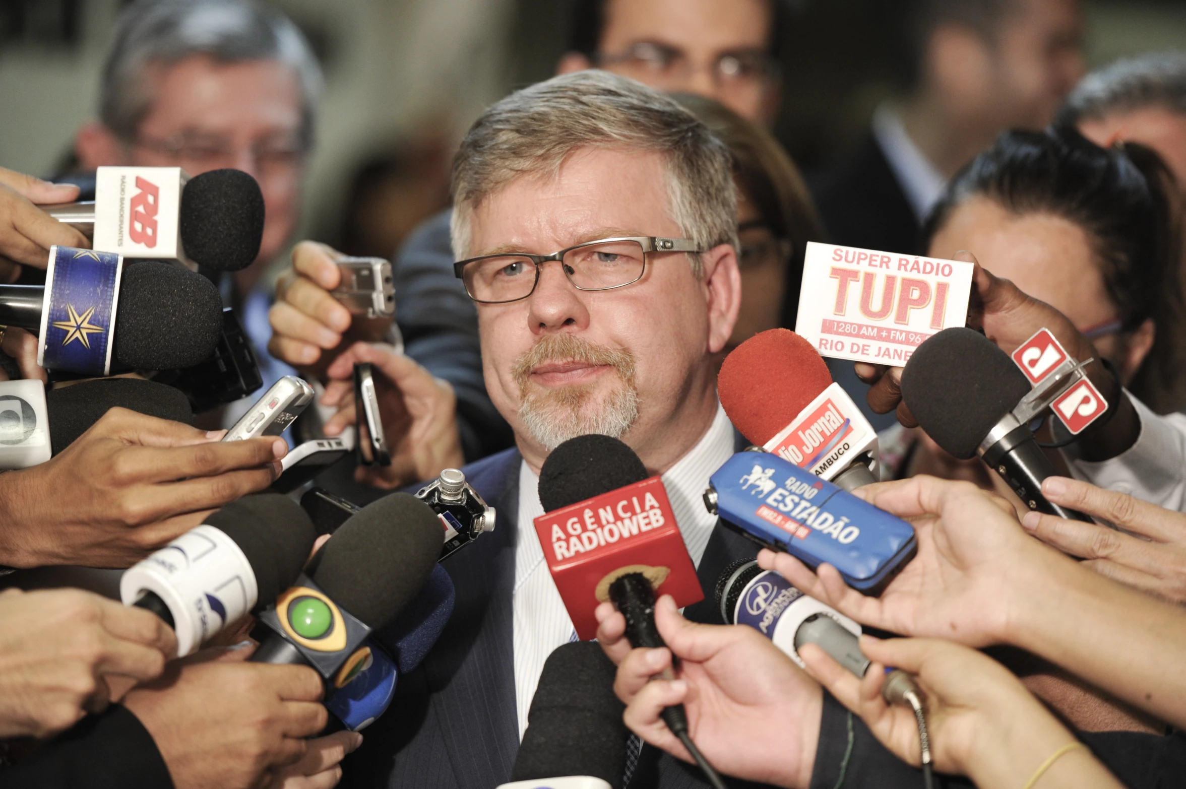 a man surrounded by reporters in suits and ties