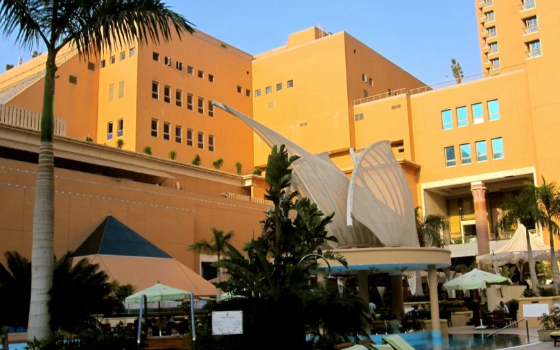 a yellow building with palm trees and chairs