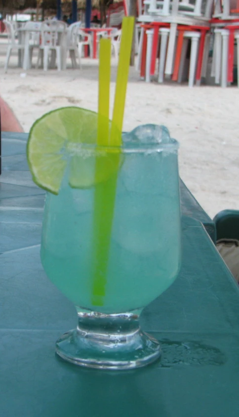a margarita drink with lime and a slice of lime on a green table