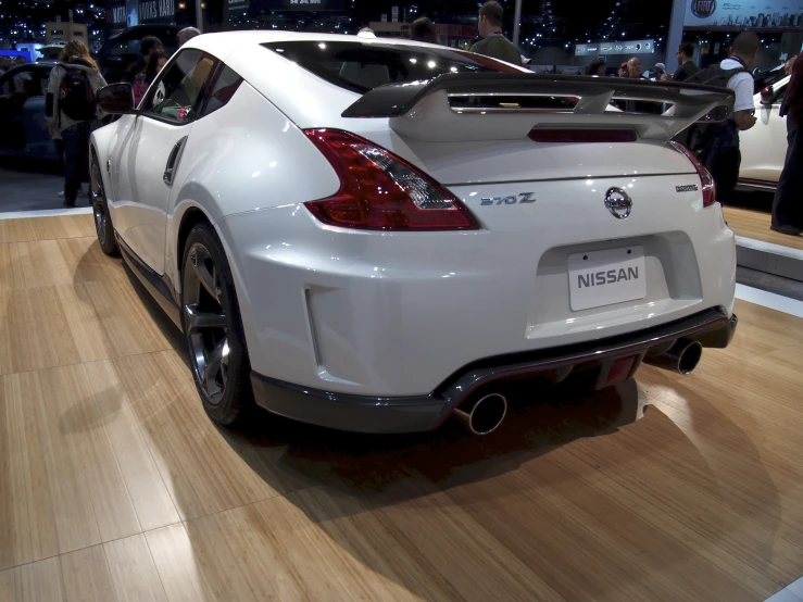 a white sports car on display on a wooden floor