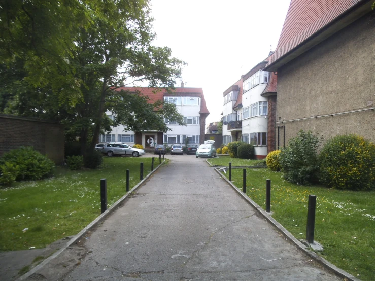 an open paved roadway with tall brick buildings and a car parked behind it