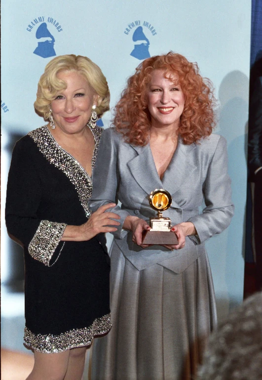 two women who are holding an award together