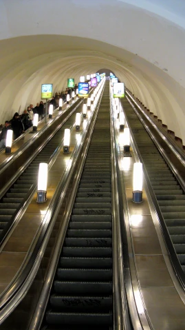 several people on an escalator going around some lights