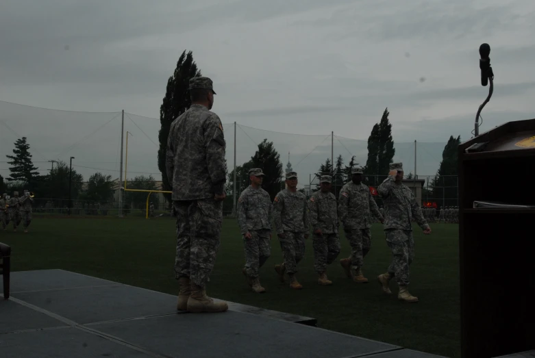 military men walking down a grass field next to each other