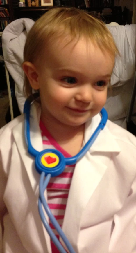 a child in a white coat with blue stethoscope