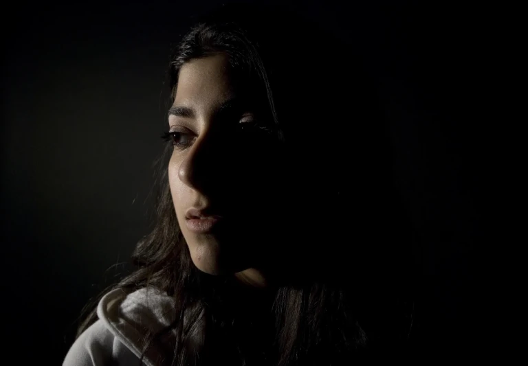 a woman standing in the dark with long hair