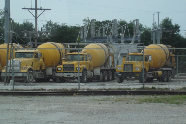 several large yellow tankers parked behind a fence