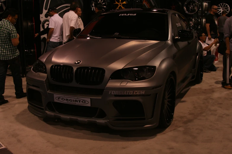 several people standing around a very shiny gray bmw