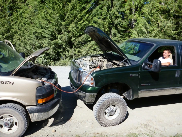 the man is next to his truck with its hood open